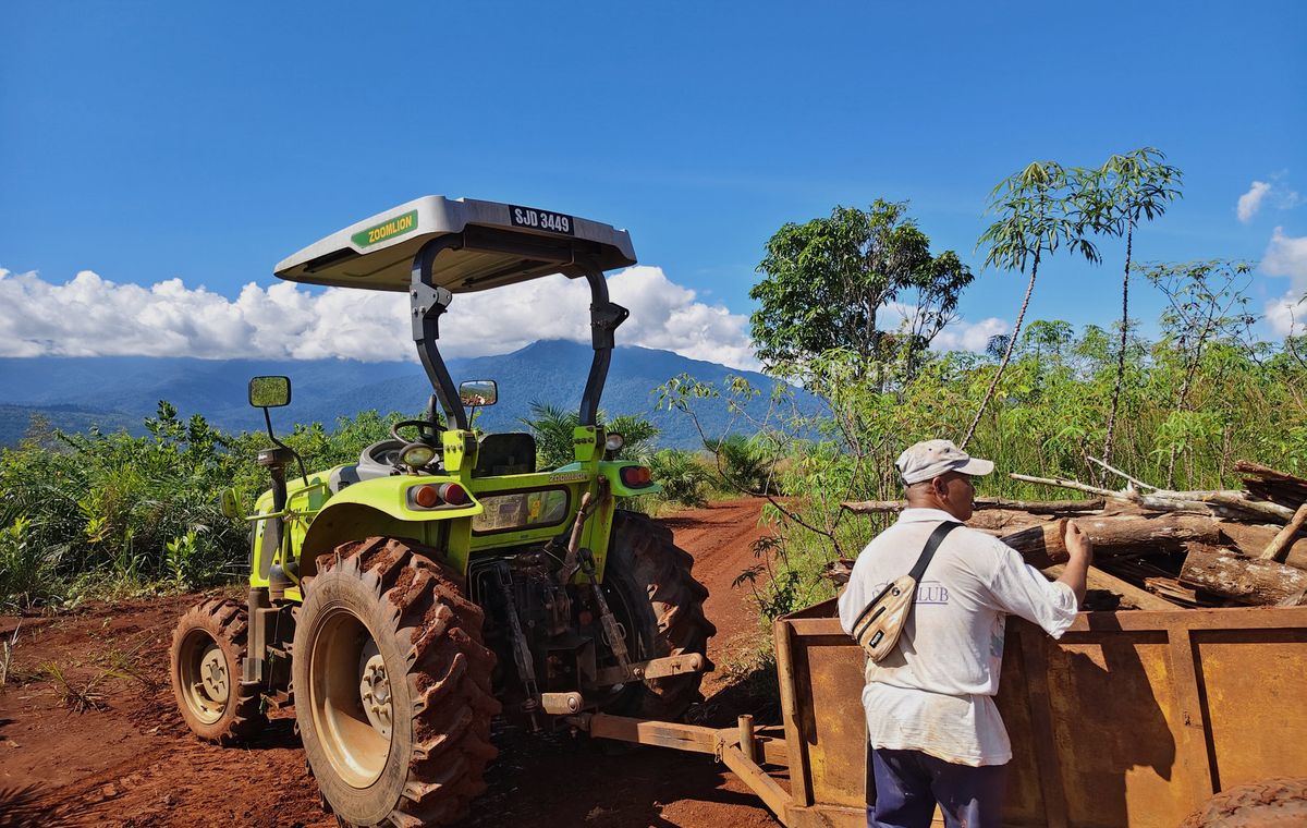 Tractor and trailer moving mill residue on red soil at the Soil and Flame site in Malaysia